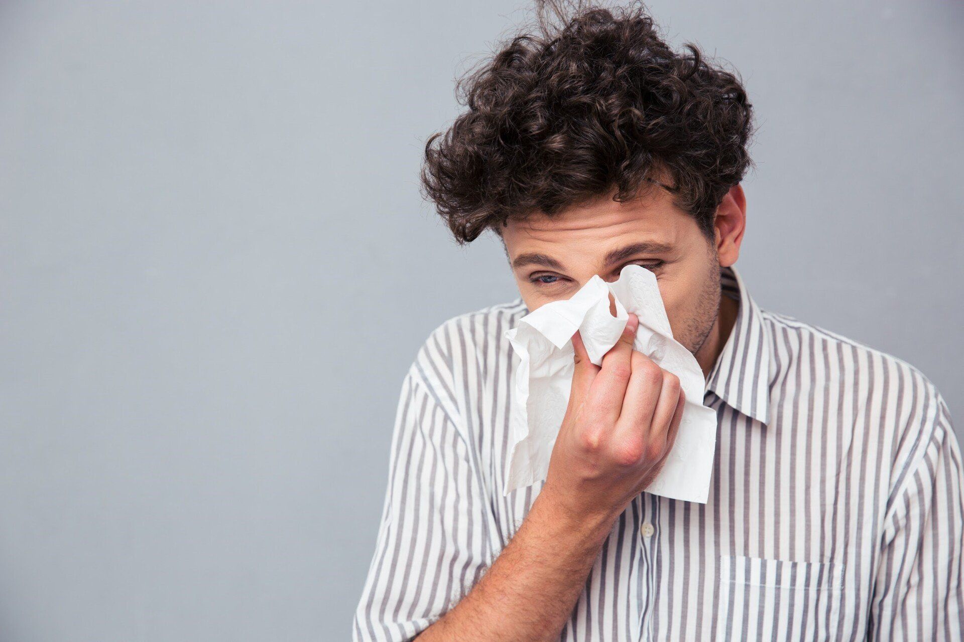 Man having nasal problems blowing his nose on a tissue
