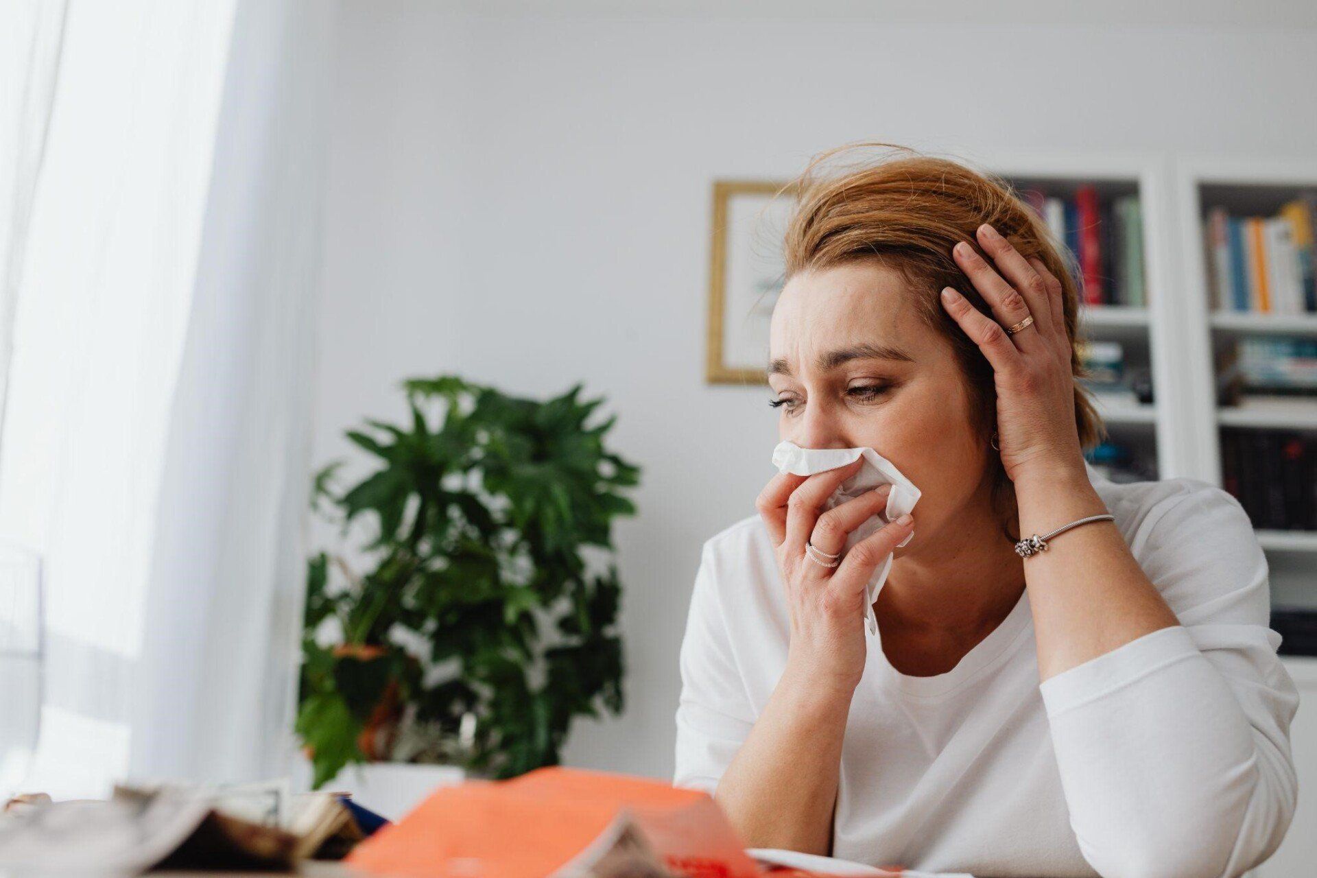 Woman with a tissue on her nose and is suffering from sinus problems