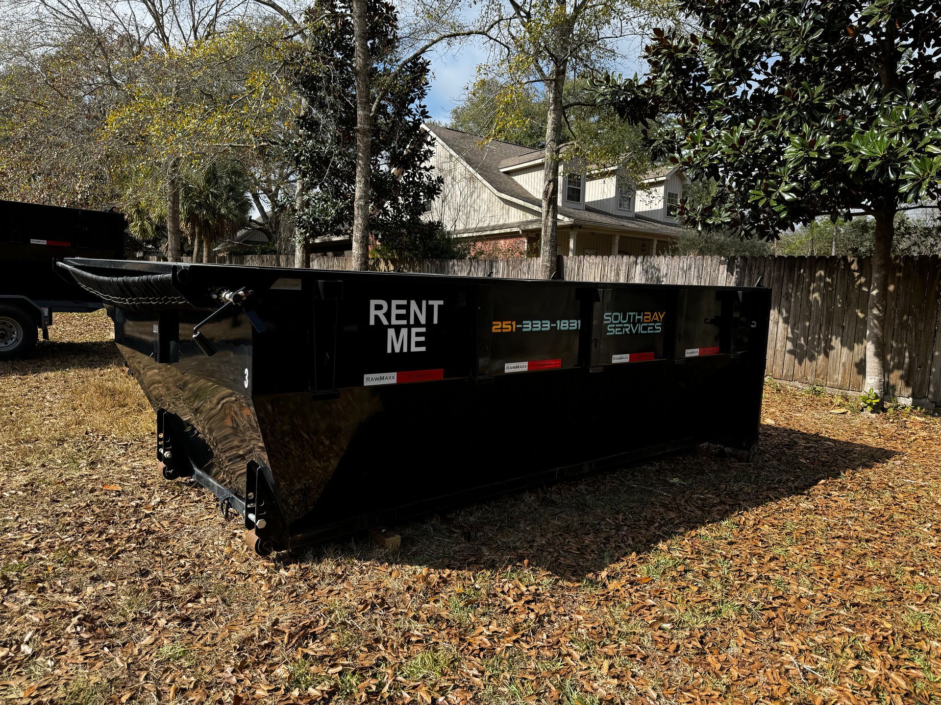 Black dumpster on grass with 