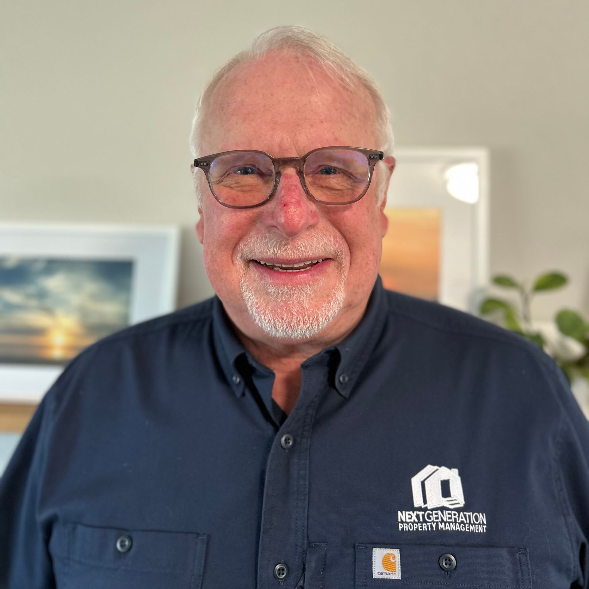 A man wearing glasses and a blue shirt is smiling for the camera.