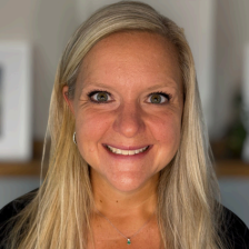 A woman wearing a black hoodie is smiling for the camera.