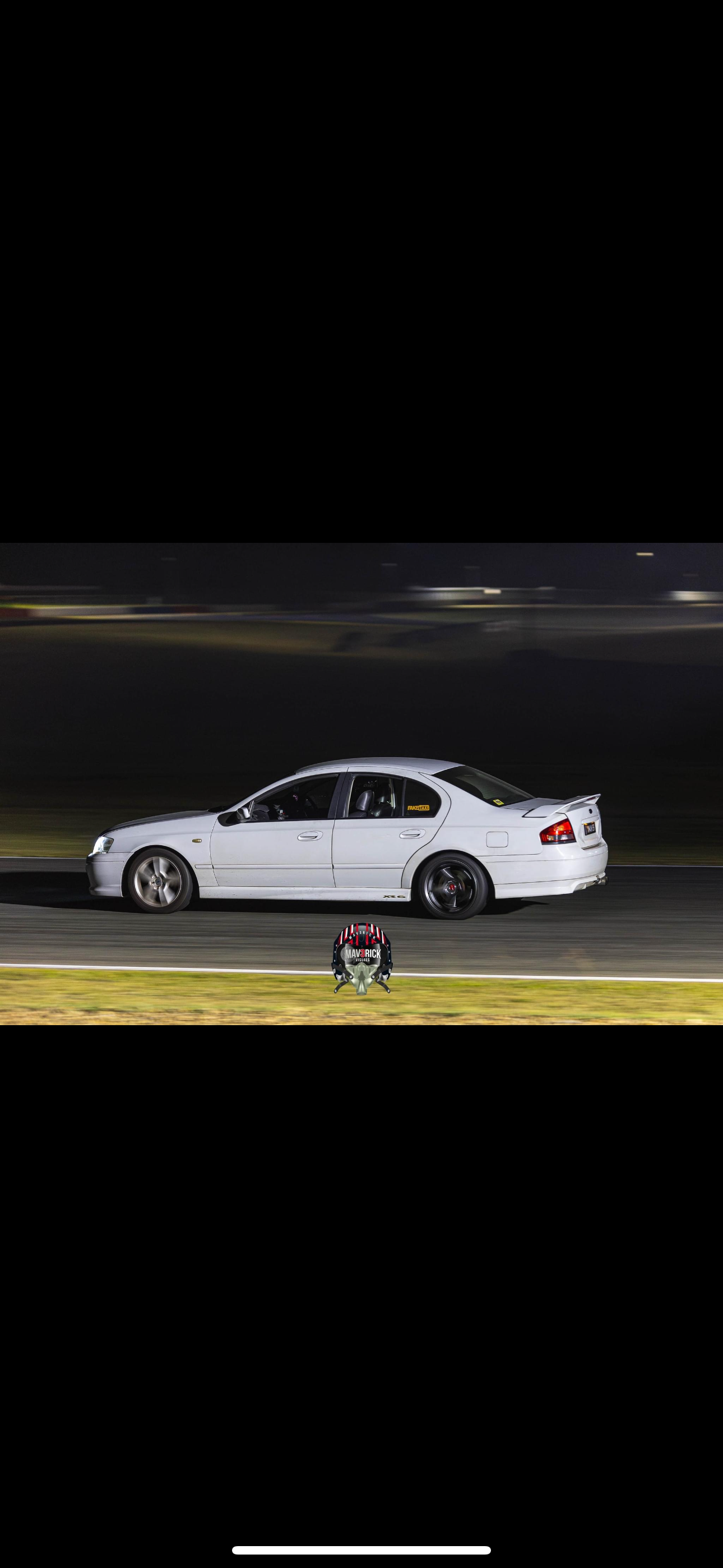 A white car is driving down a race track at night. — HO Performance in Cleveland, QLD