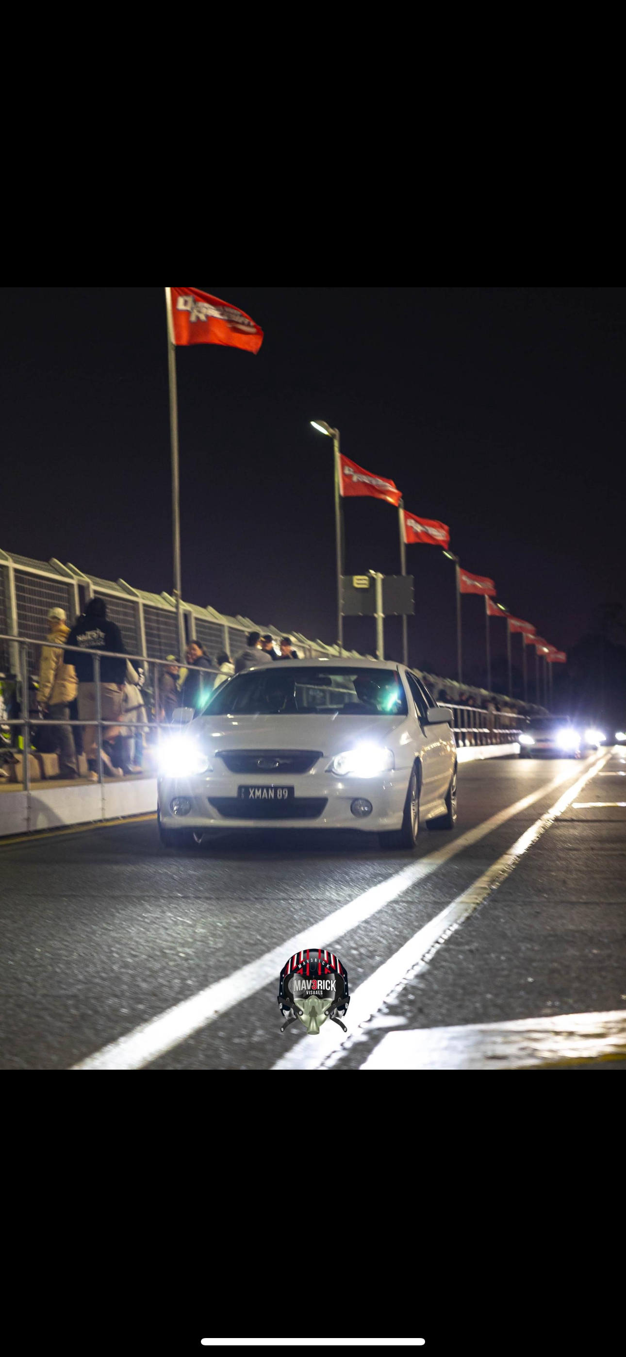A white car is driving down a race track at night. — HO Performance in Cleveland, QLD