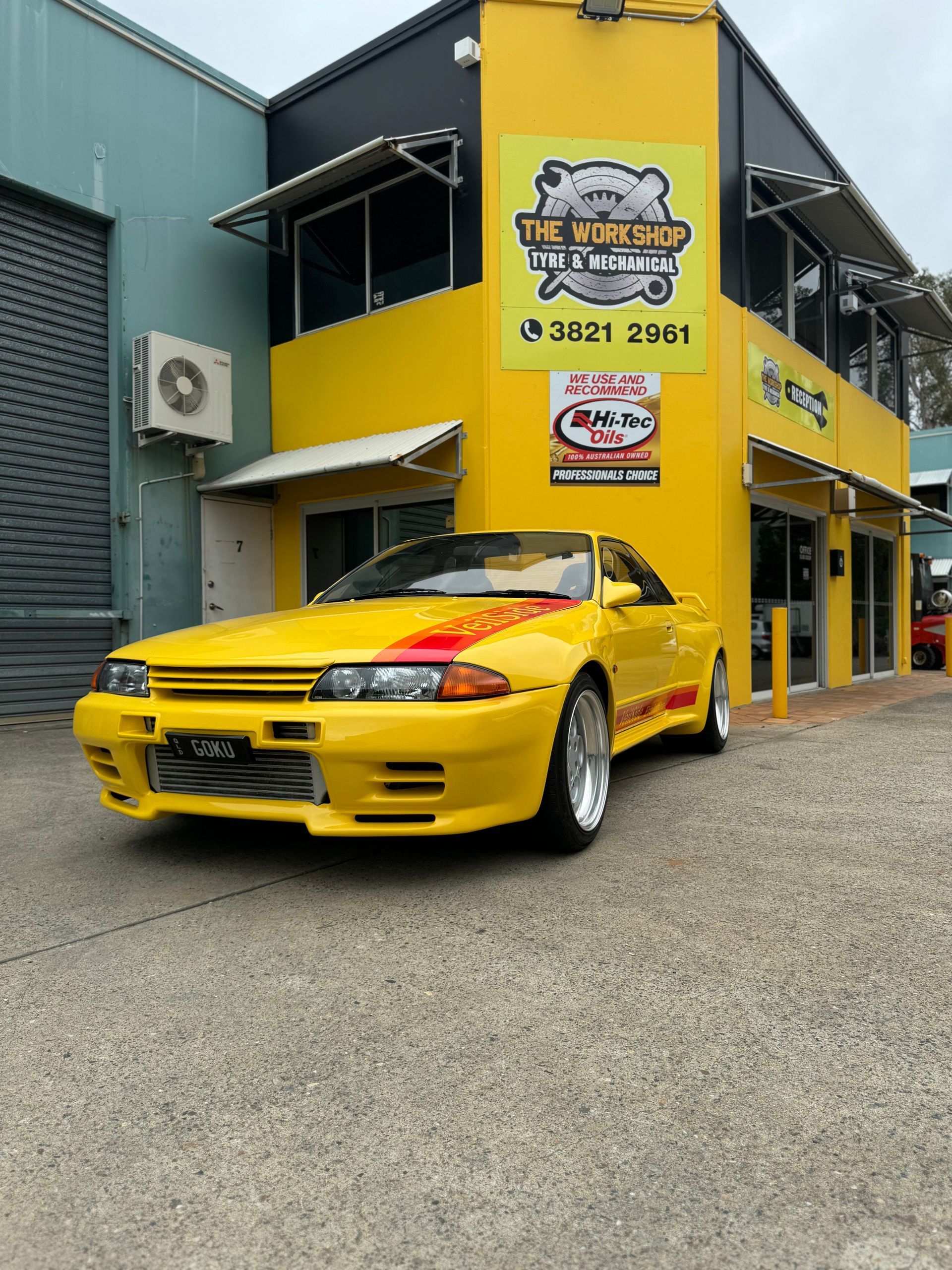 A yellow car is parked in front of a yellow building. — HO Performance in Cleveland, QLD