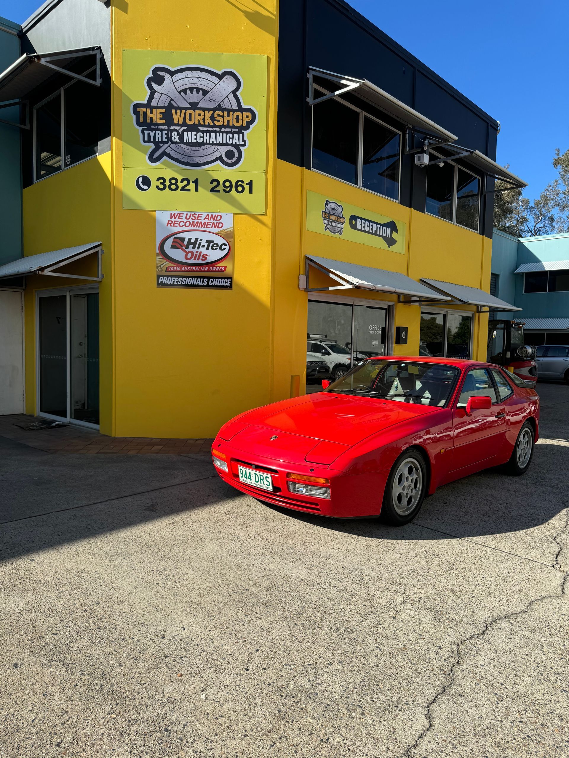A red car is parked in front of a yellow building. — HO Performance in Cleveland, QLD