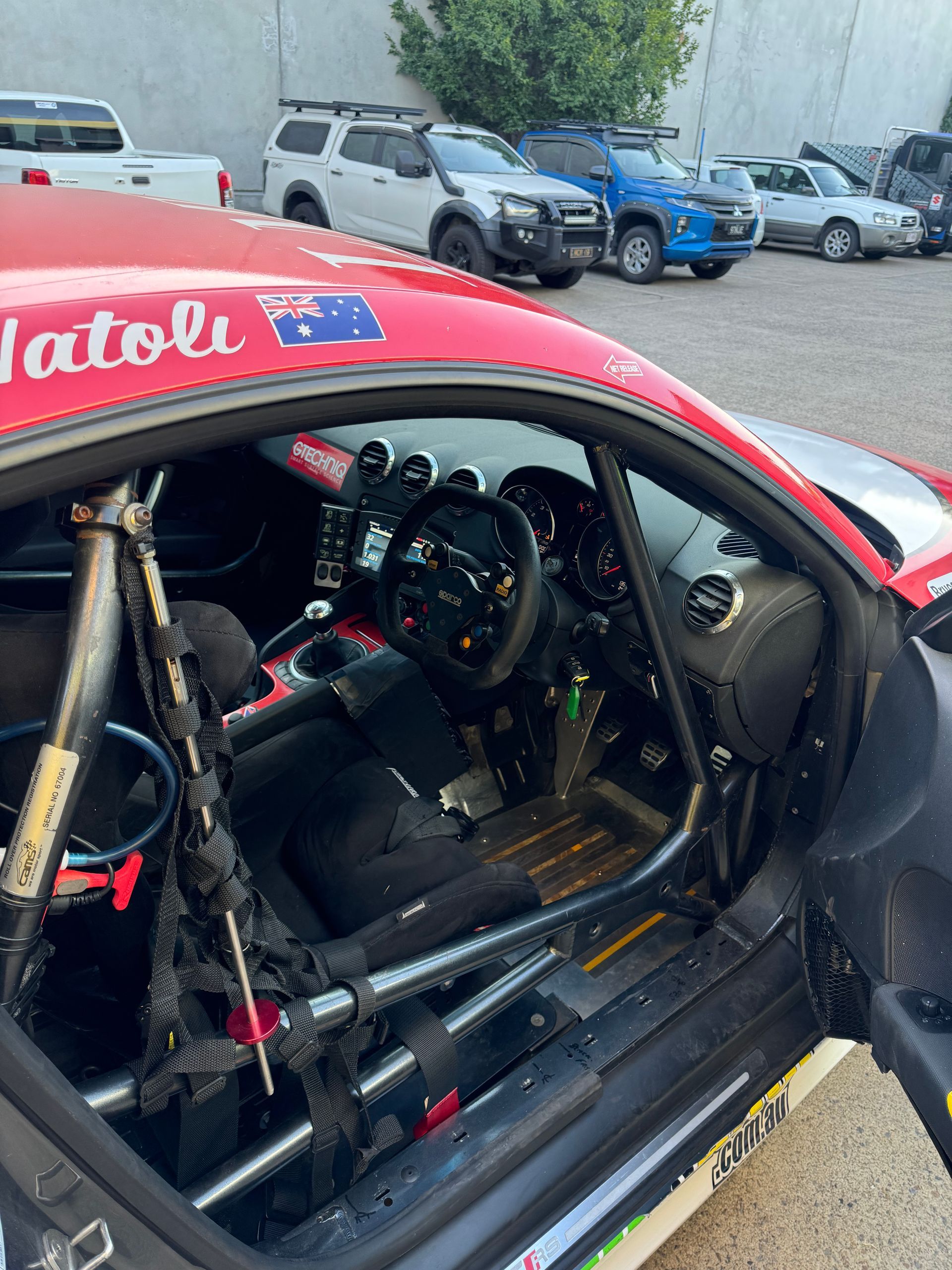 A red race car is parked in a parking lot. — HO Performance in Cleveland, QLD