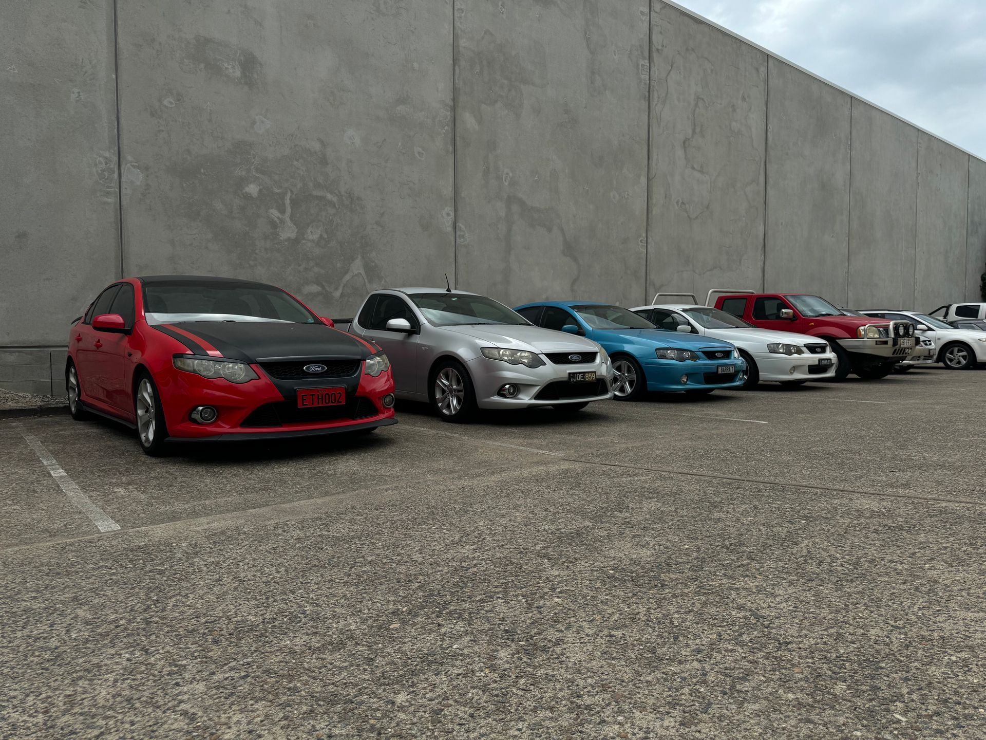 A row of cars are parked in a parking lot in front of a building. — HO Performance in Cleveland, QLD