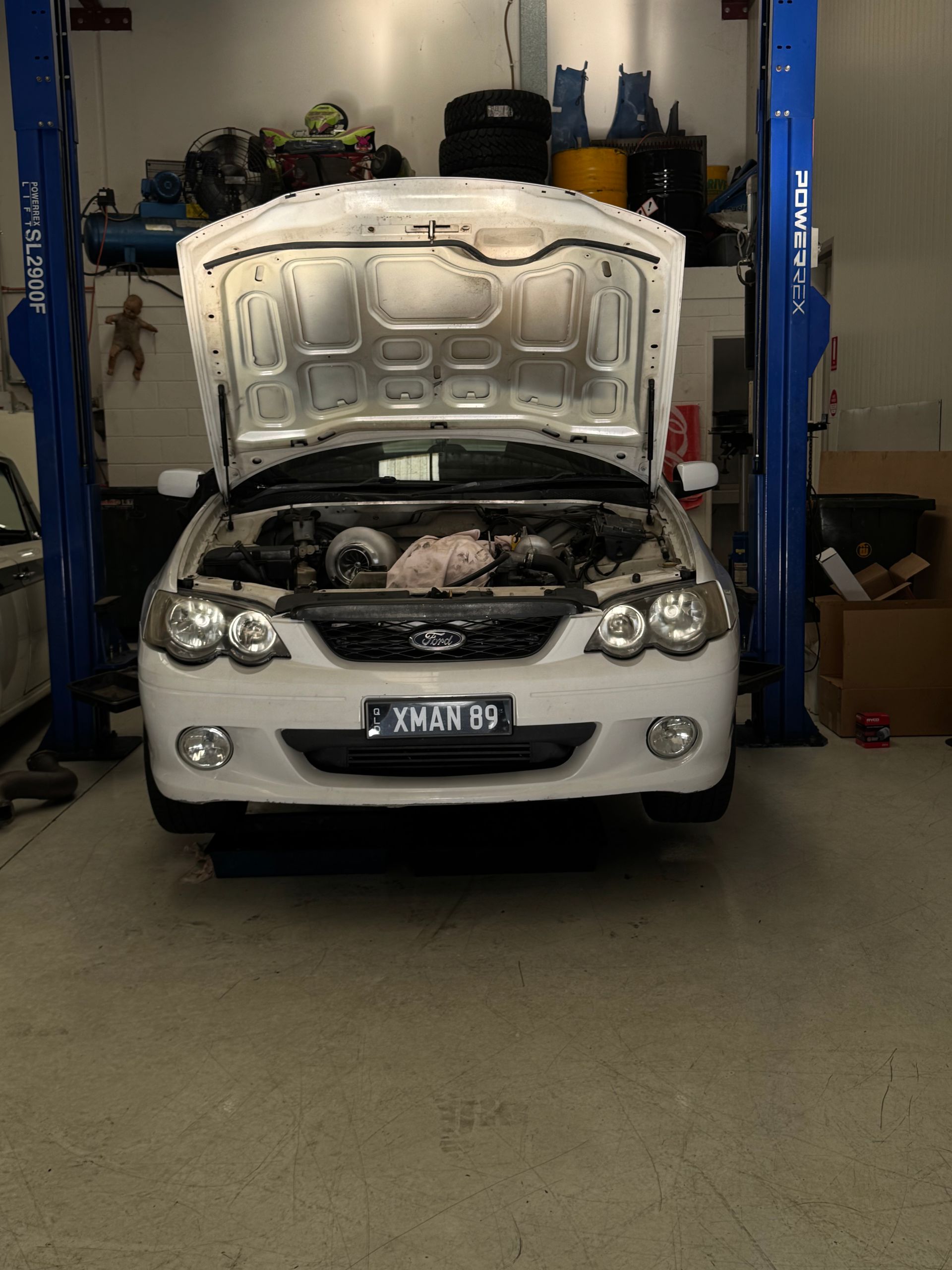 A white car is on a lift with the hood open — HO Performance in Cleveland, QLD
