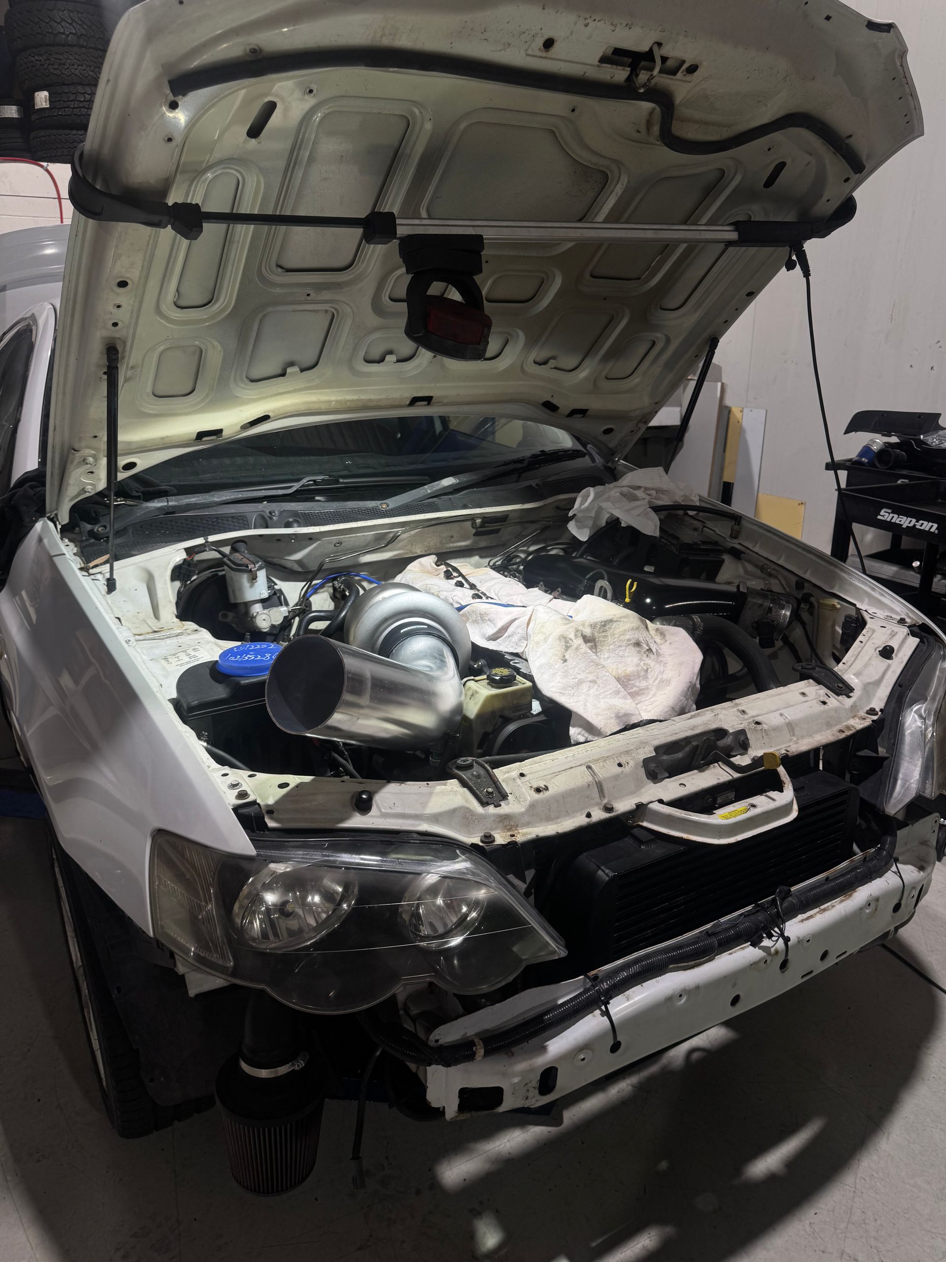 A white car with the hood open is sitting in a garage. — HO Performance in Cleveland, QLD