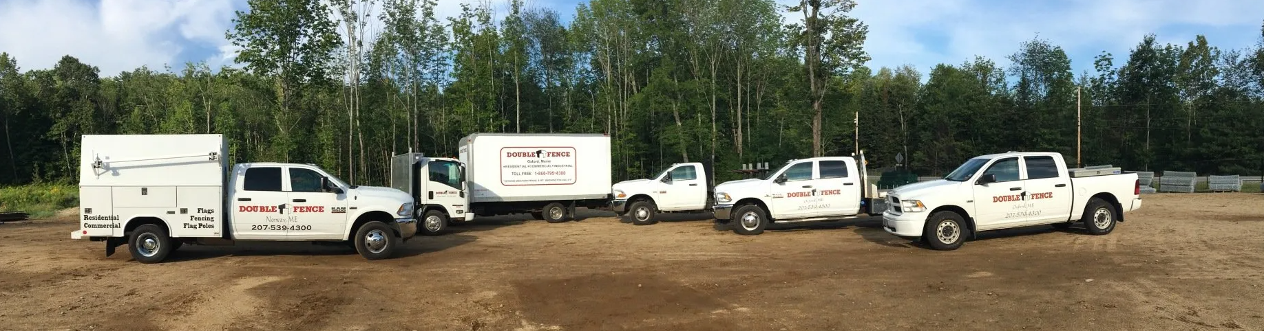 a row of white trucks are parked in a dirt lot .