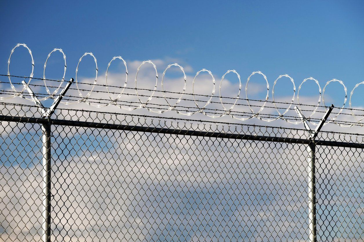 a barbed wire fence with a blue sky in the background