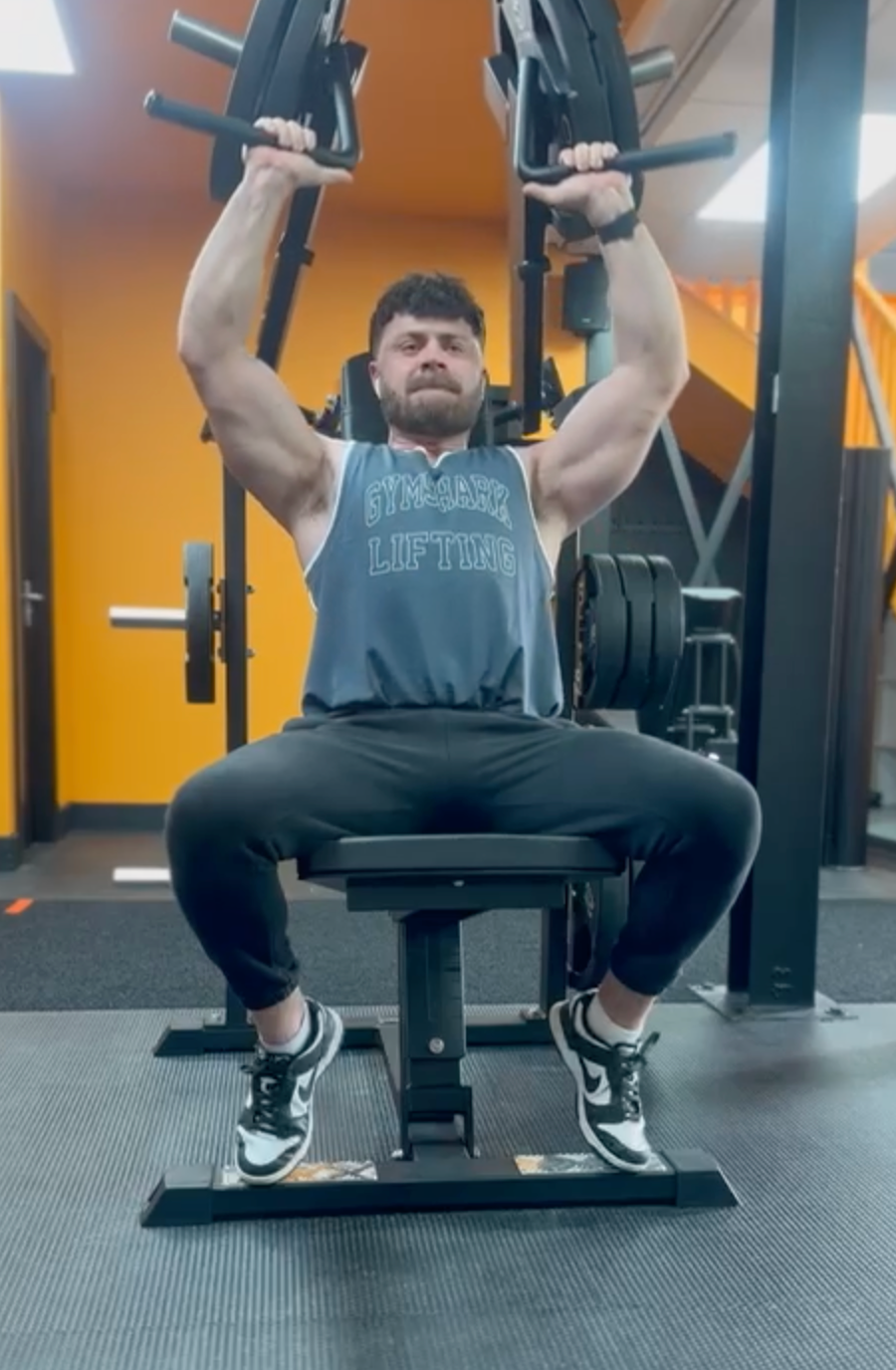 A man is sitting on a bench in a gym lifting weights