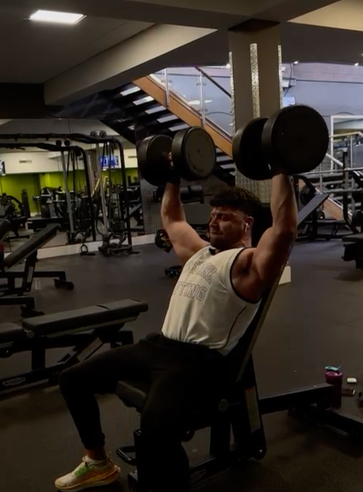 A man is lifting dumbbells in a gym