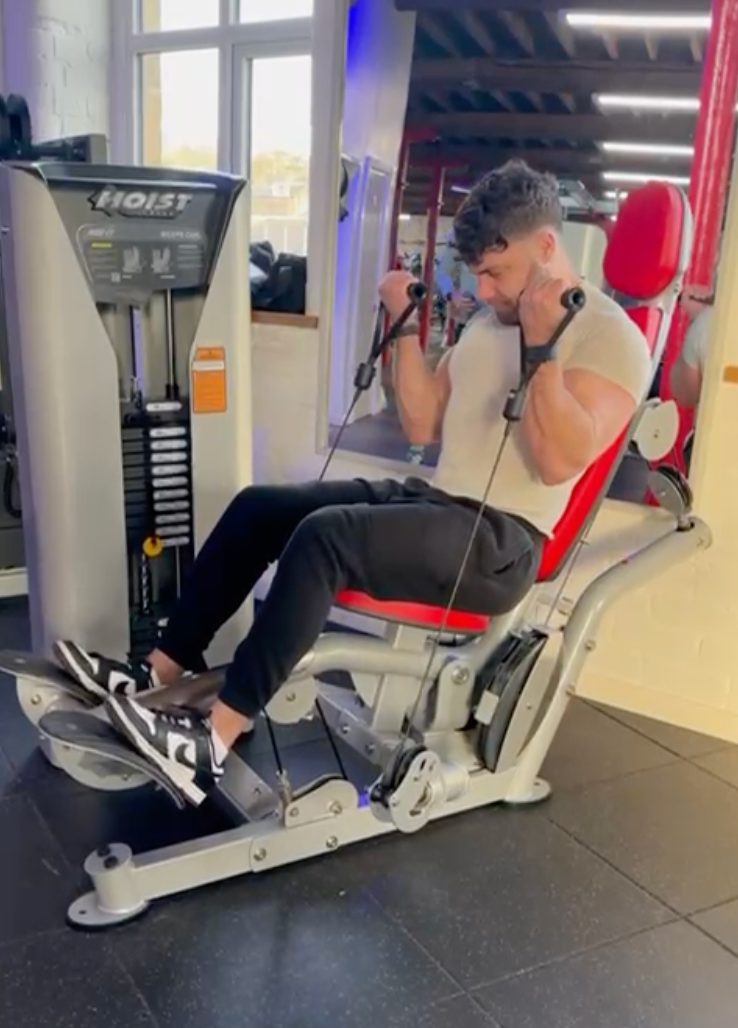 A man is sitting on a machine in a gym
