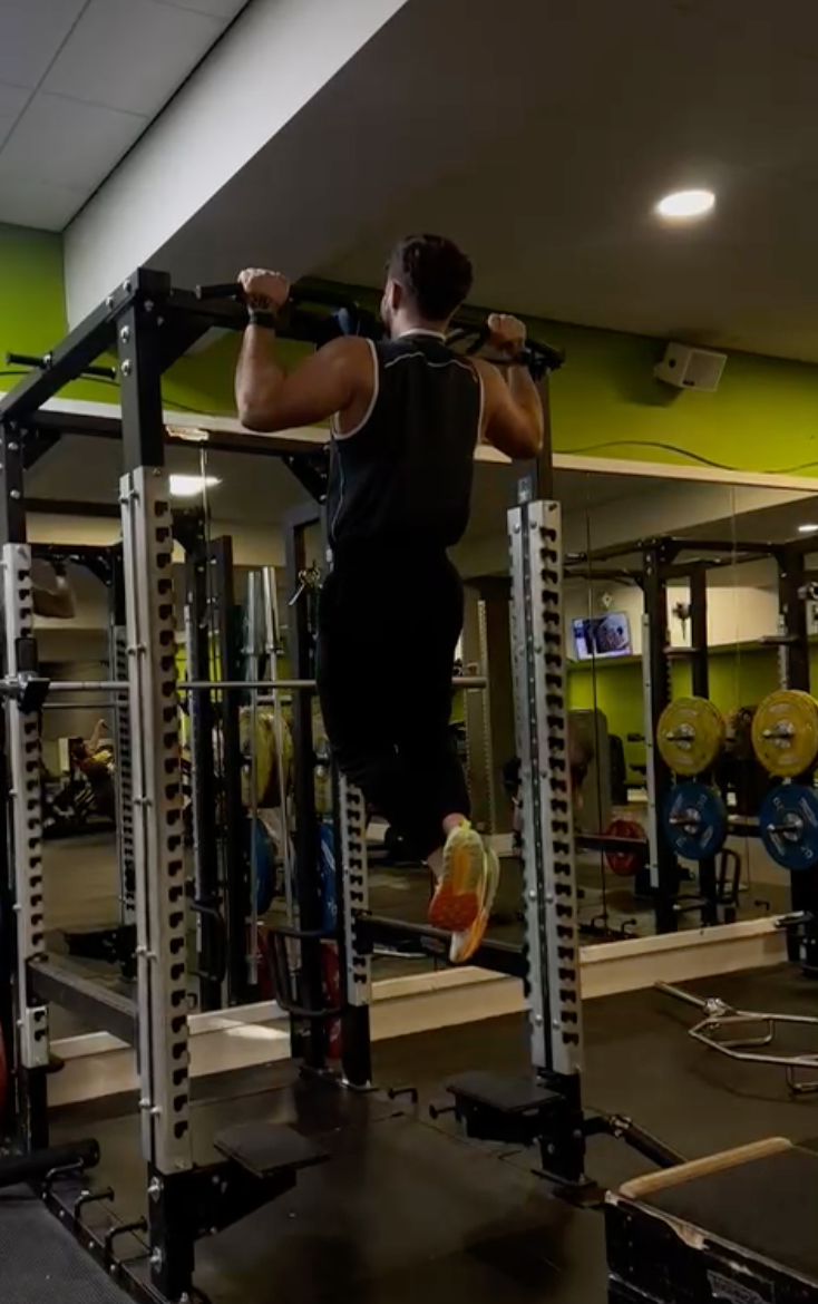 A man is doing pull ups in a gym