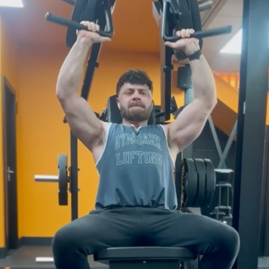 A man in a gym wearing a tank top that says lifting