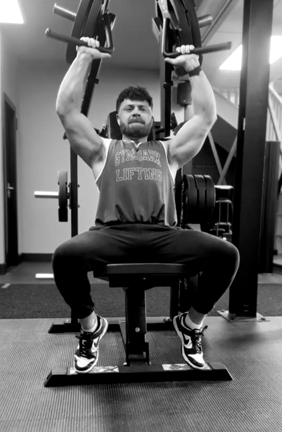 A man is sitting on a bench in a gym lifting weights.