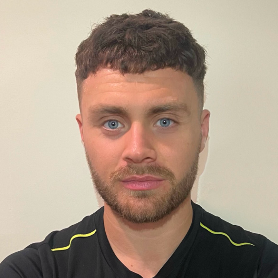 A man with a beard and blue eyes is wearing a black shirt