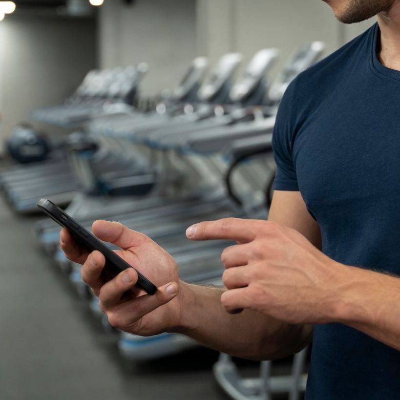 A man is using a cell phone in a gym