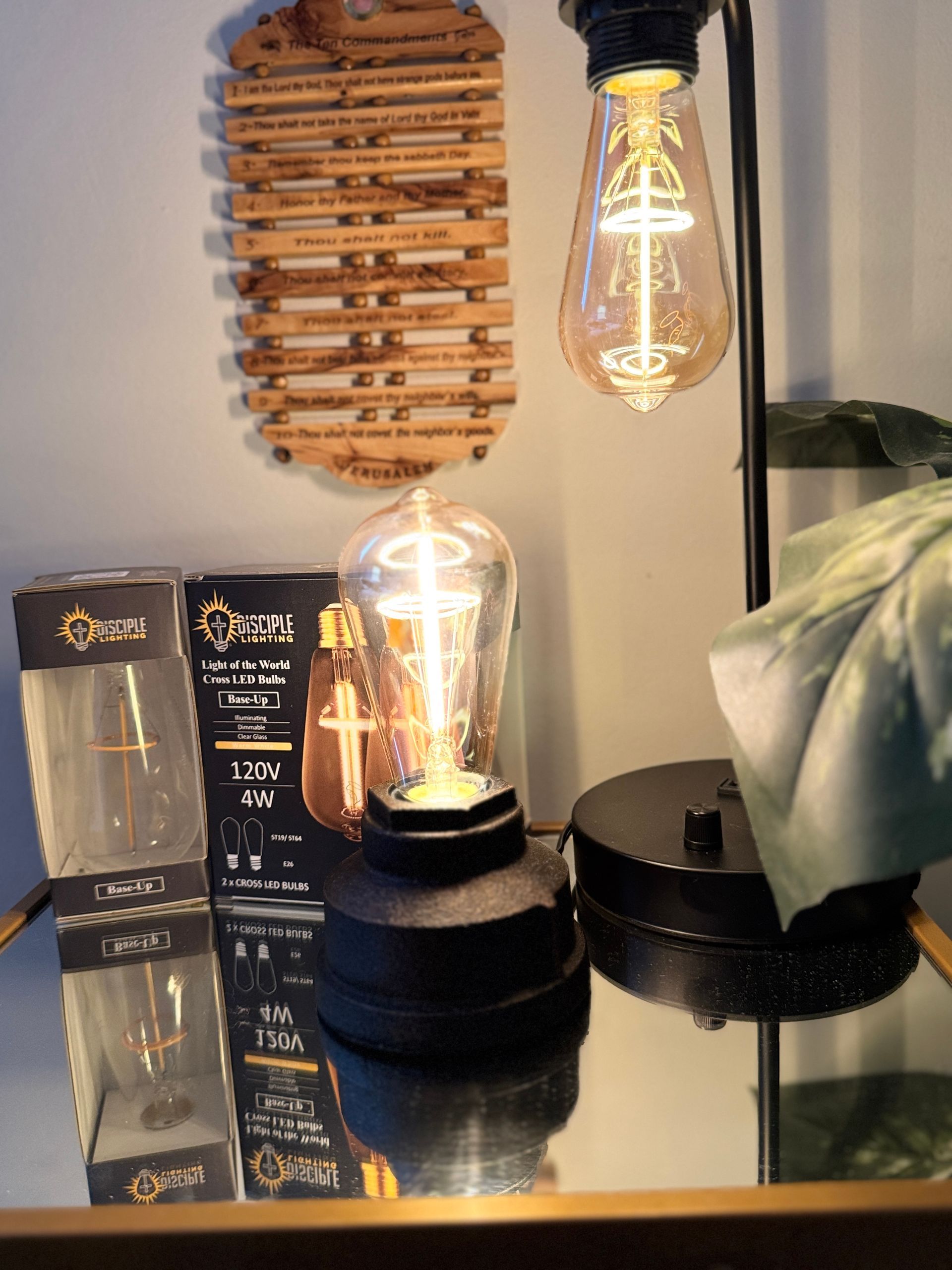 Tabletop lamp with a vintage-style bulb next to the box it came in and a wooden wall decoration.