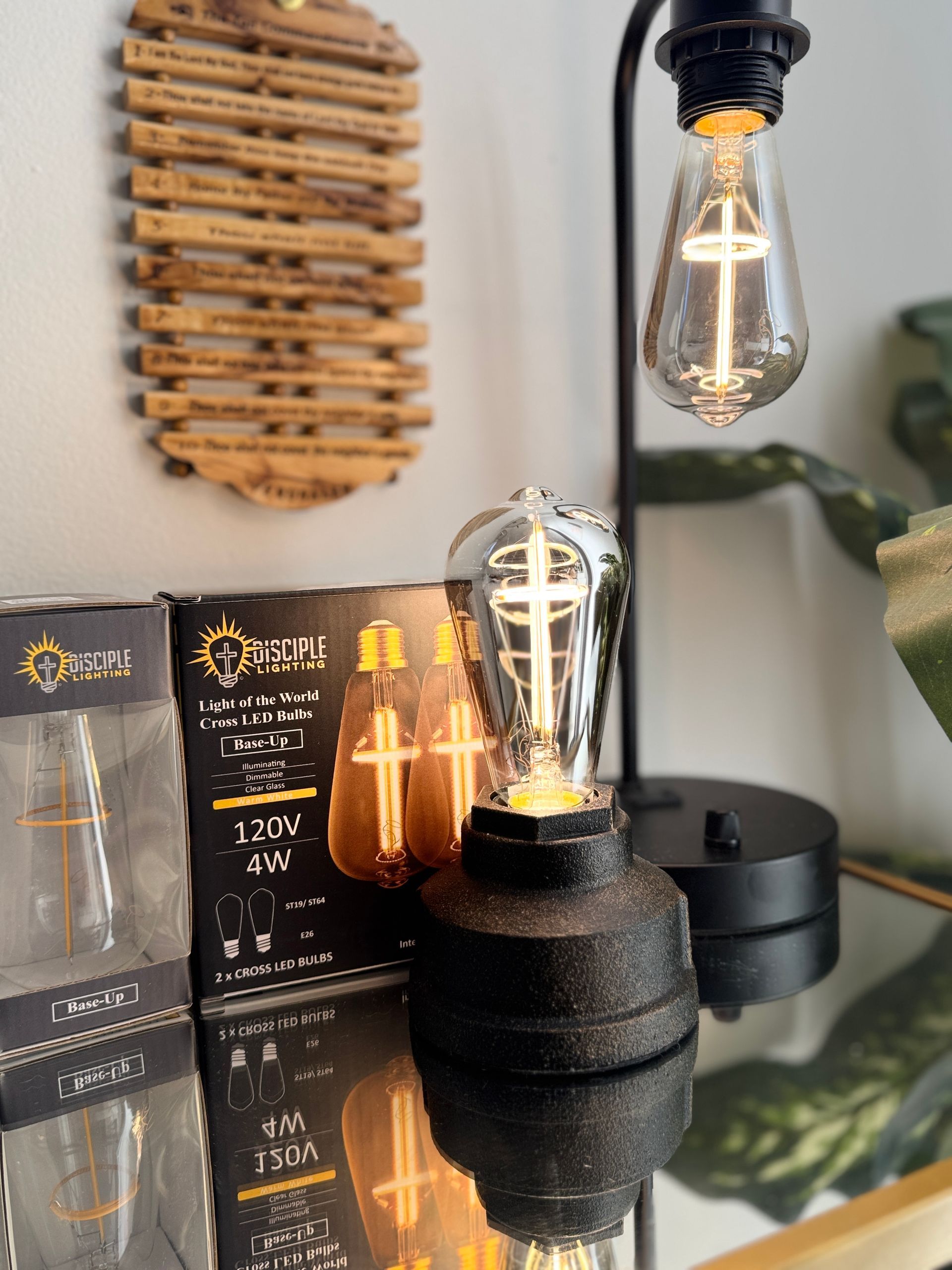 Black desk lamp with Edison bulb, next to product packaging and decorative wooden art.
