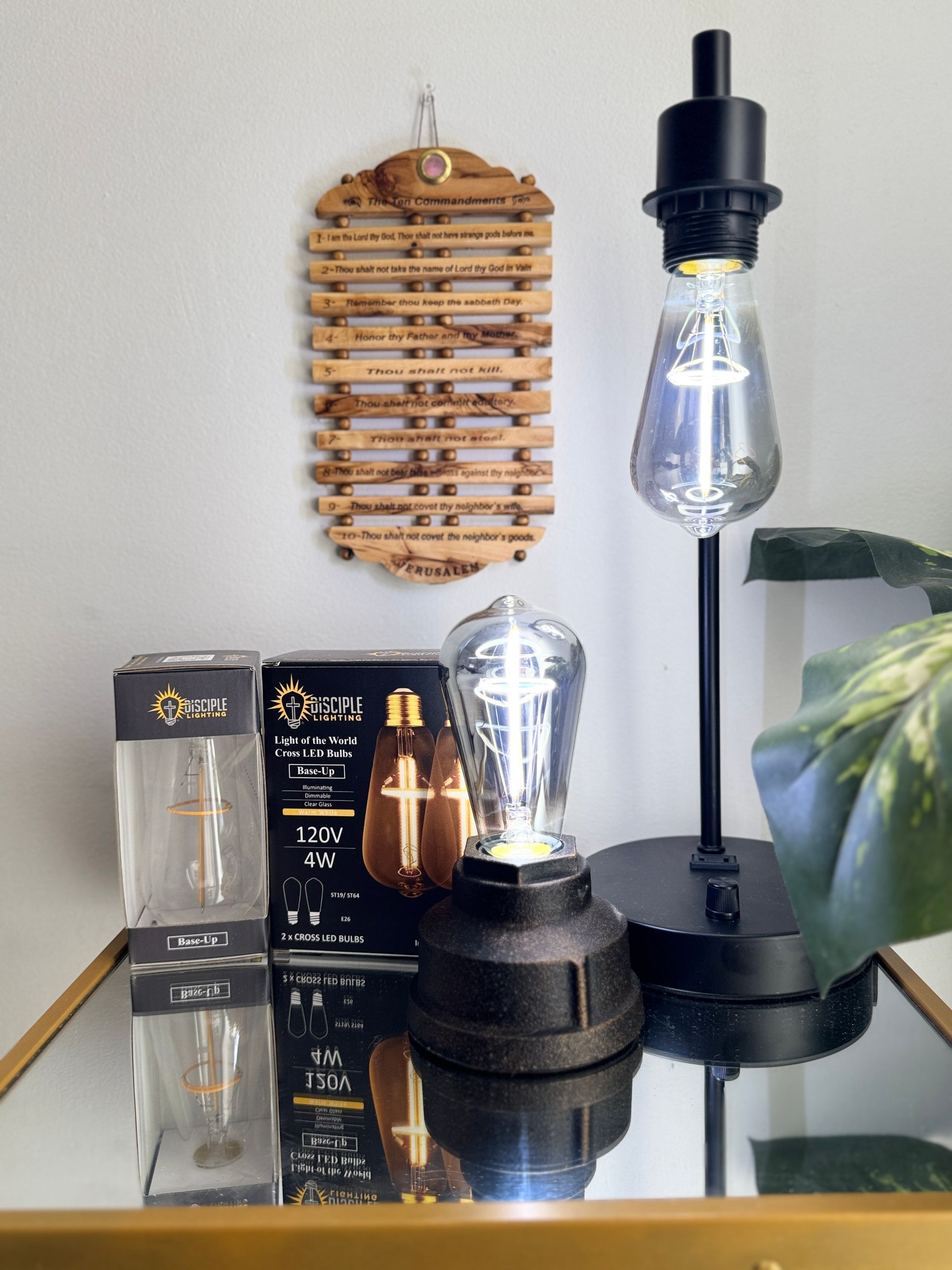 A table lamp and two decorative light bulbs displayed on a mirrored surface next to boxes with lights.