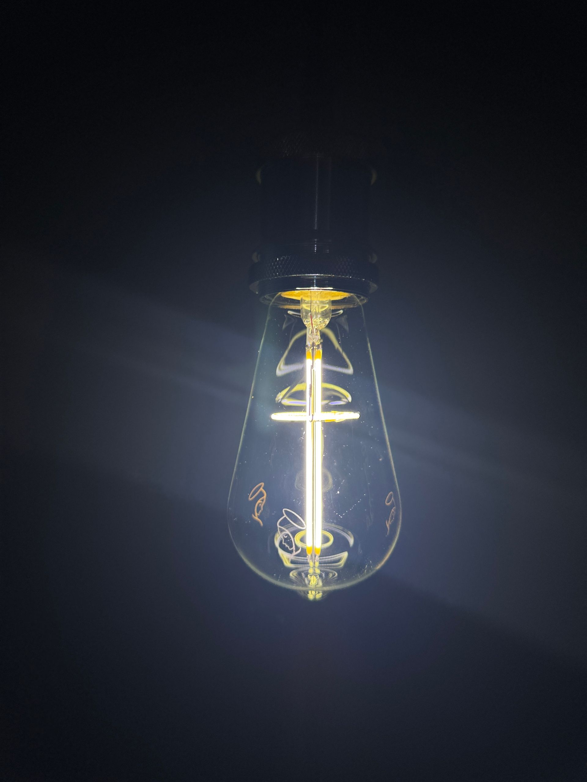 Lit Edison bulb in a dark setting, glowing with intricate internal filament.