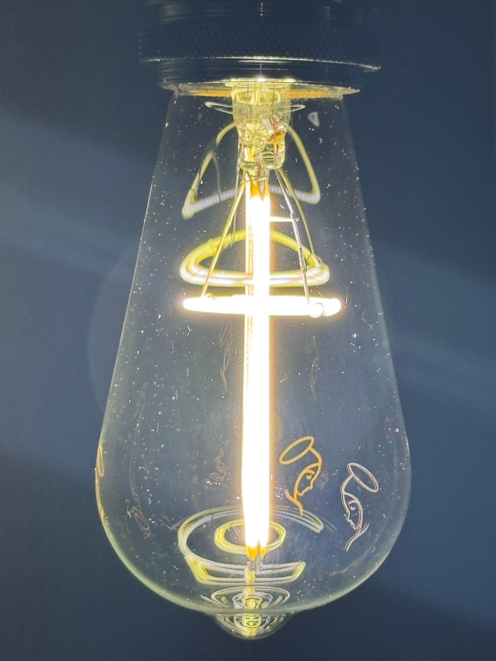 Light bulb with an angel design illuminated with a bright, vertical light.