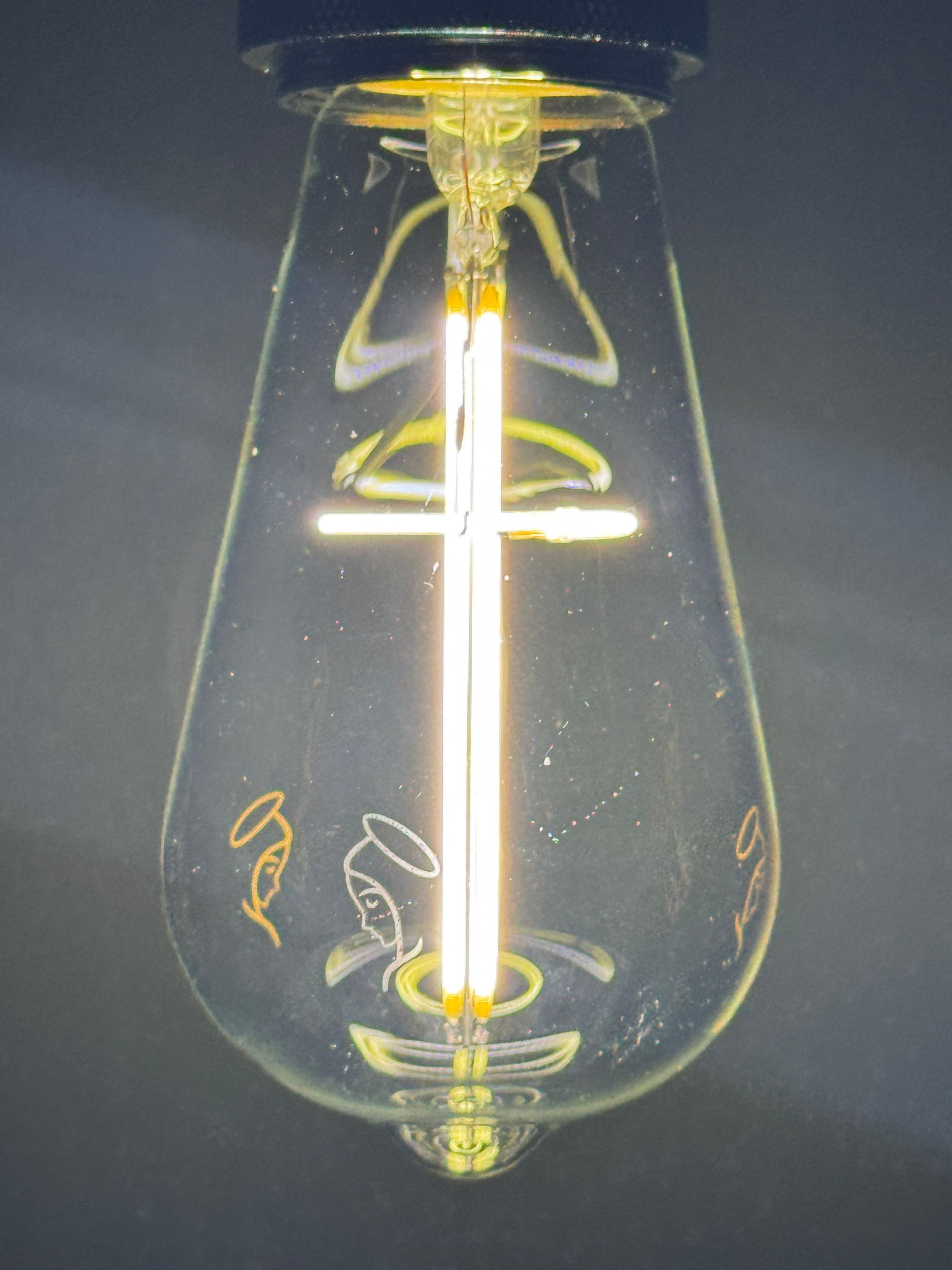 Lit bulb with a cross-shaped LED filament and etched angel designs.