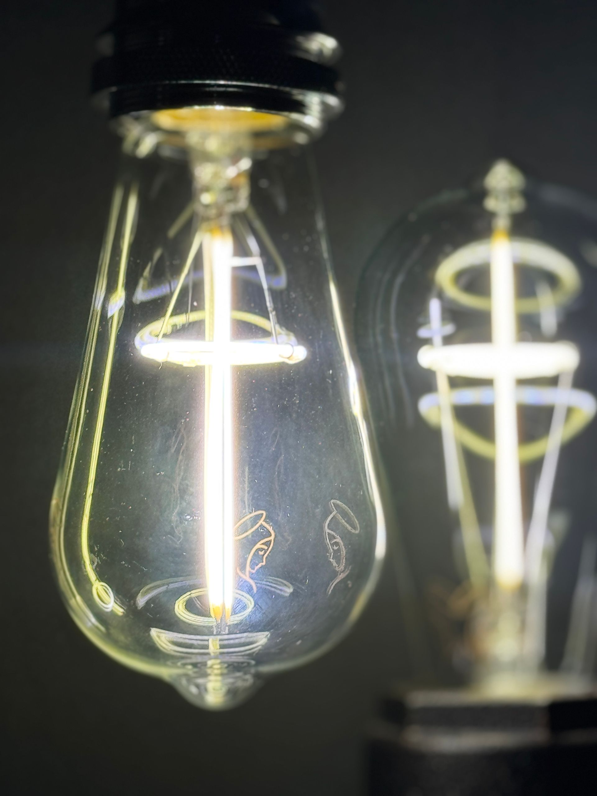 Two light bulbs with illuminated crosses.