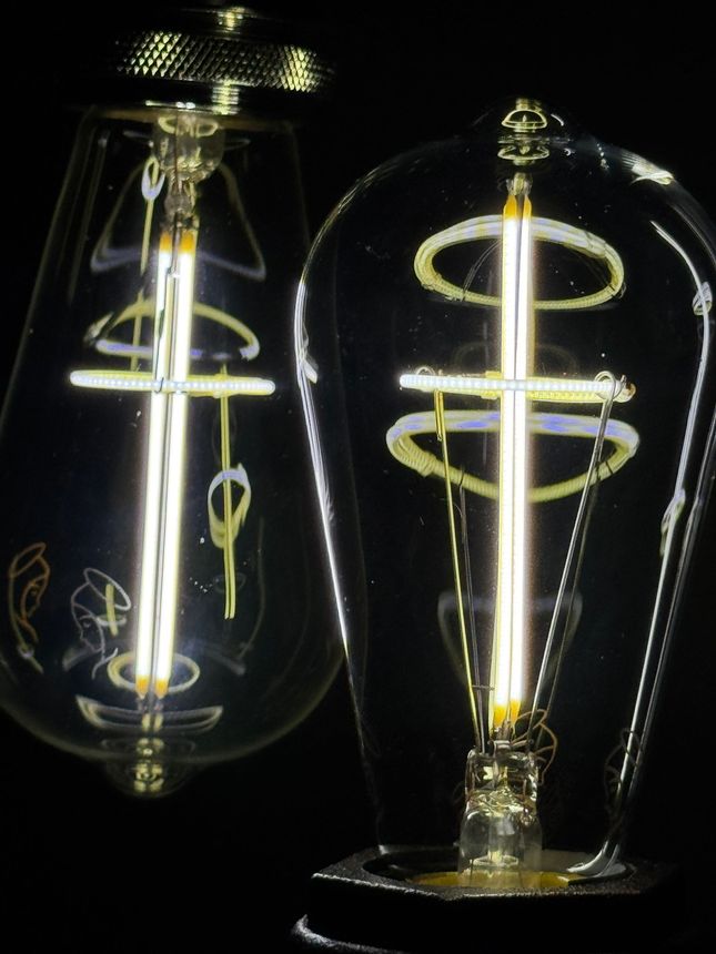 Two vintage-style Edison light bulbs with glowing filaments against a black background.