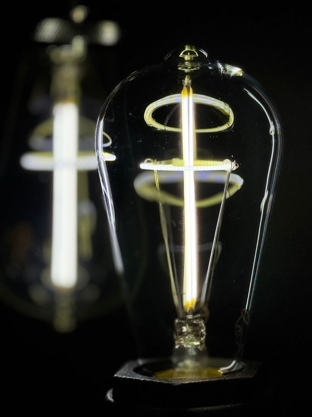 Two lit, ornate lightbulbs against a black background.