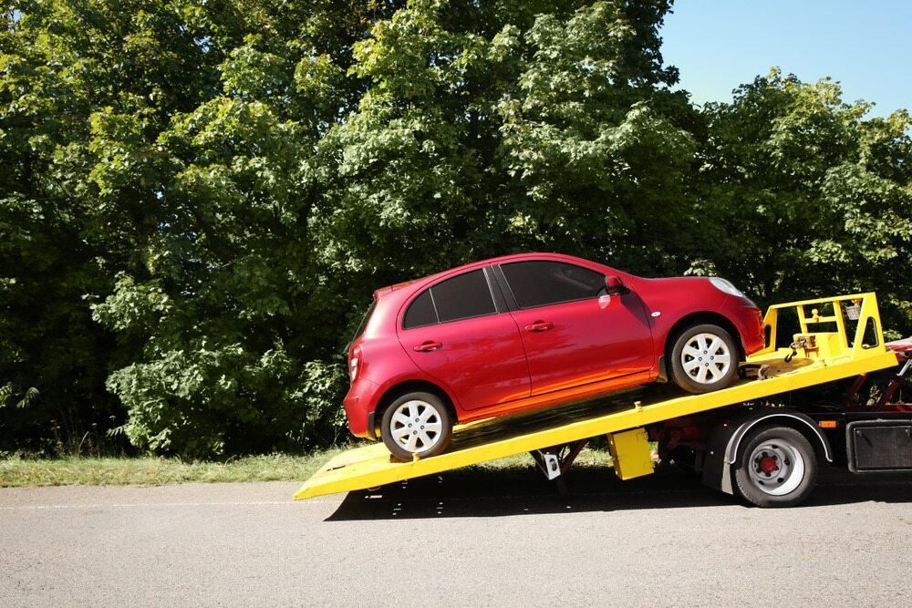 A Red Car is Being Towed by a Tow Truck — Bulahdelah Towing In Karuah, NSW