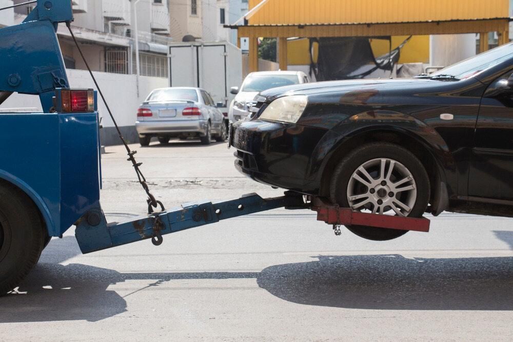 A Black Car is Being Towed by a Blue Tow Truck — Bulahdelah Towing In Bulahdelah, NSW