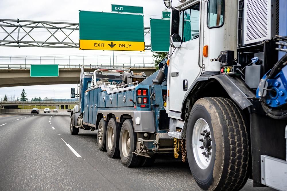A Tow Truck is Driving Down a Highway Under a Bridge — Bulahdelah Towing In Karuah, NSW