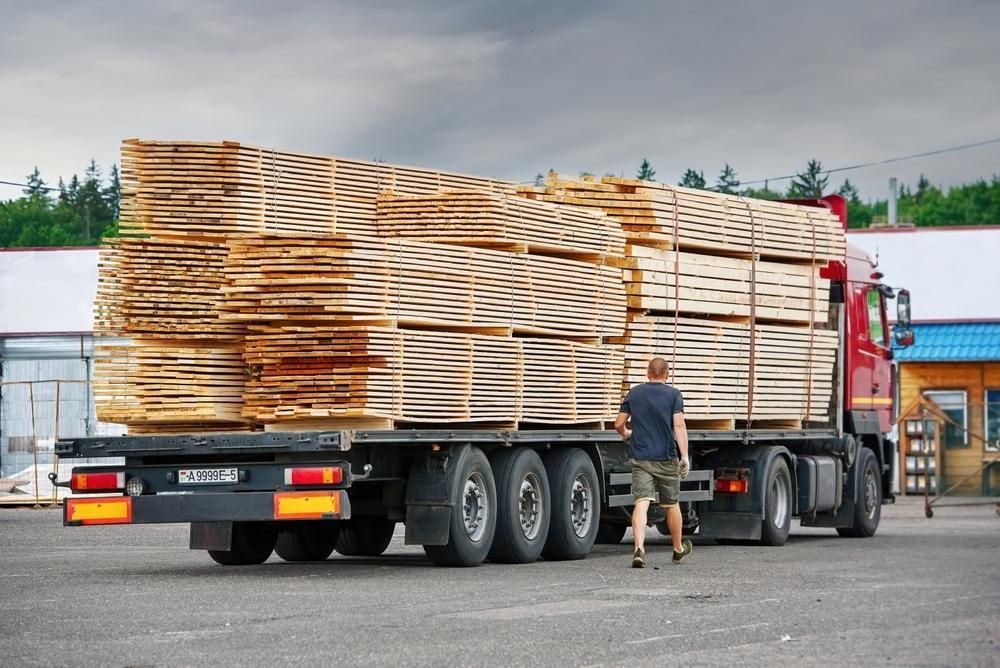 A Man is Pushing a Truck With a Stack of Wood on the Back — Bulahdelah Towing In Stroud, NSW