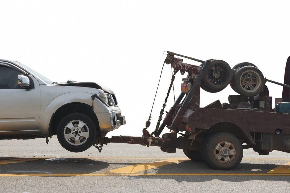 A Tow Truck is Towing a Damaged Car on the Side of the Road — Bulahdelah Towing In Karuah, NSW