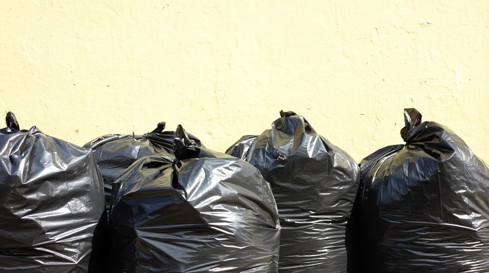 Black Trash Bags Against a Beige Wall — Tamworth Skips and Rubbish Removal in Quirindi, NSW