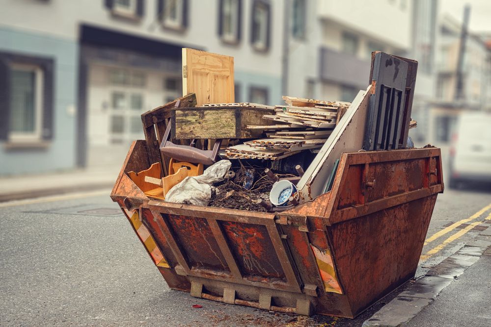 Rusty Dumpster Overflowing With Debris on a City Street — Tamworth Skips and Rubbish Removal in South Tamworth, NSW