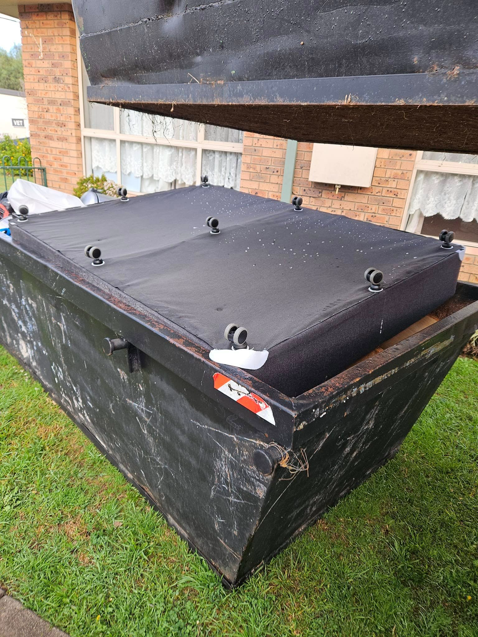 Black Dumpster With Open Lid on a Grassy Lawn — Tamworth Skips and Rubbish Removal in South Tamworth, NSW