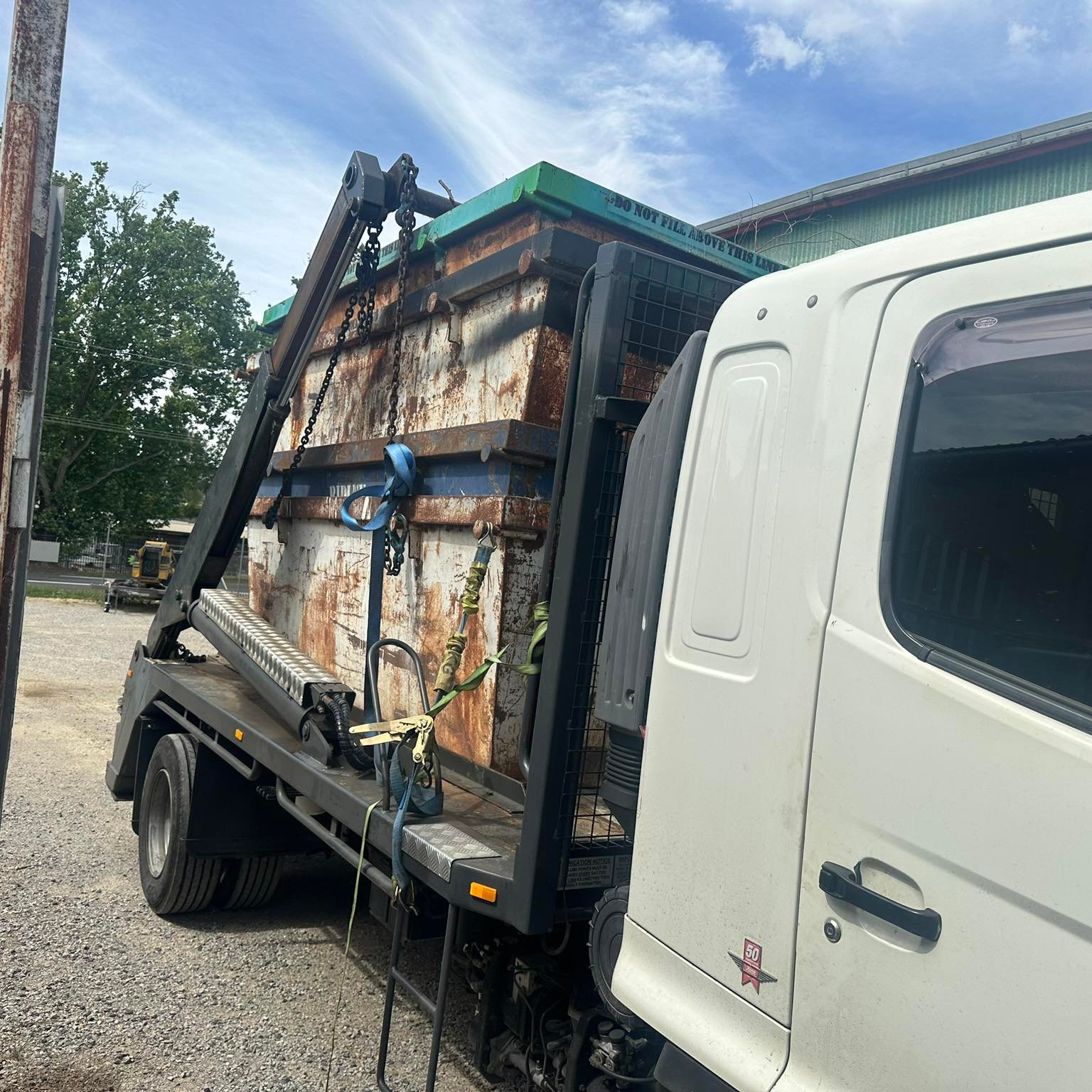 White Truck With a Rusty Dumpster Being Hauled — Tamworth Skips and Rubbish Removal in South Tamworth, NSW