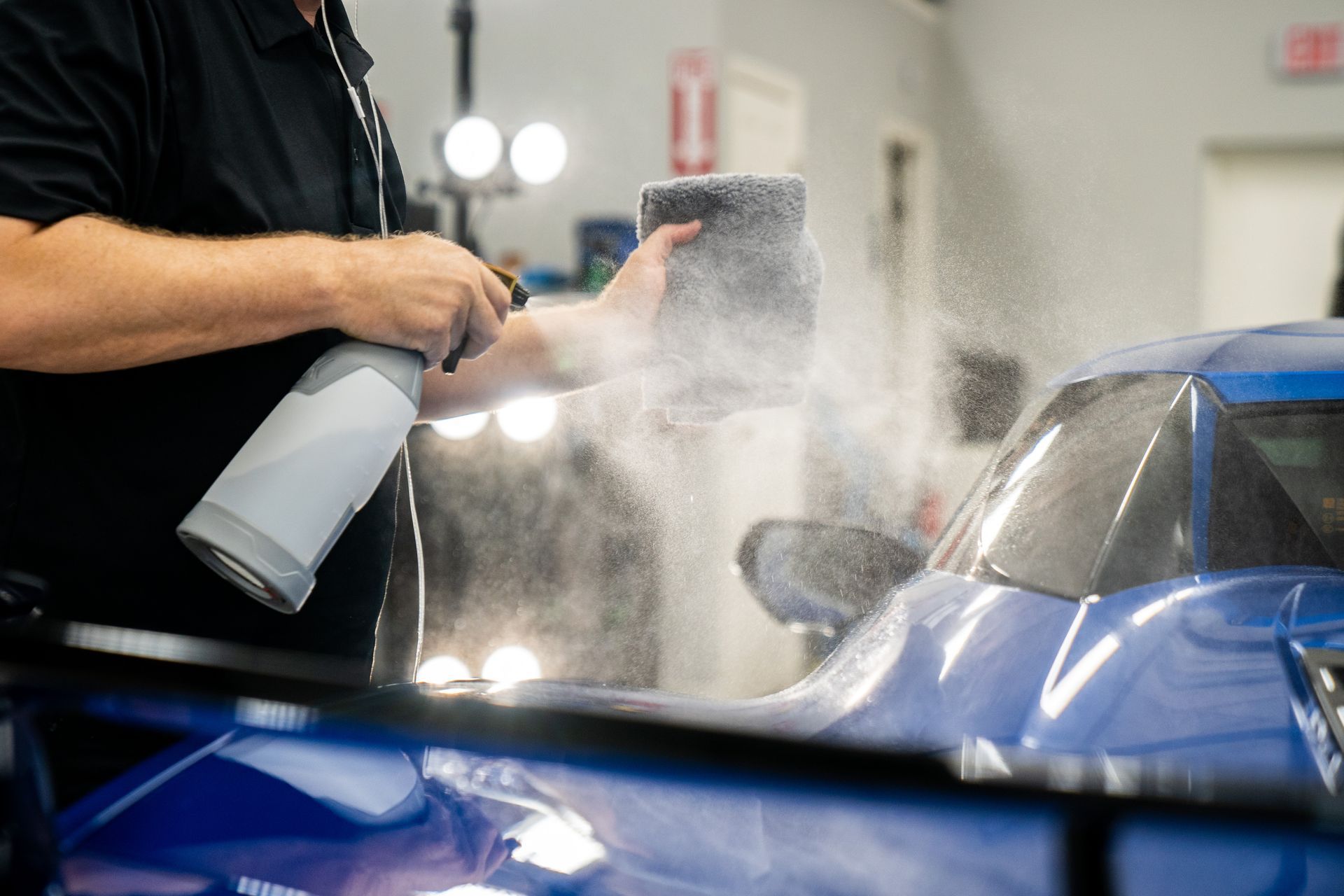 A man is washing a car with foam in a garage.