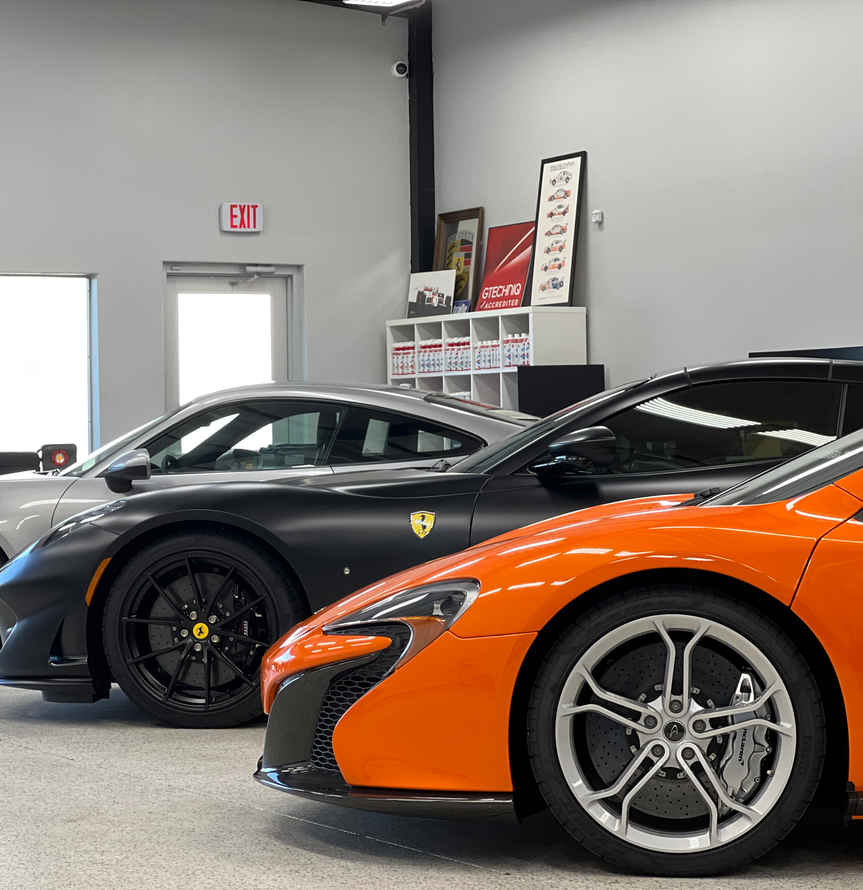 A green sports car is parked next to a white car