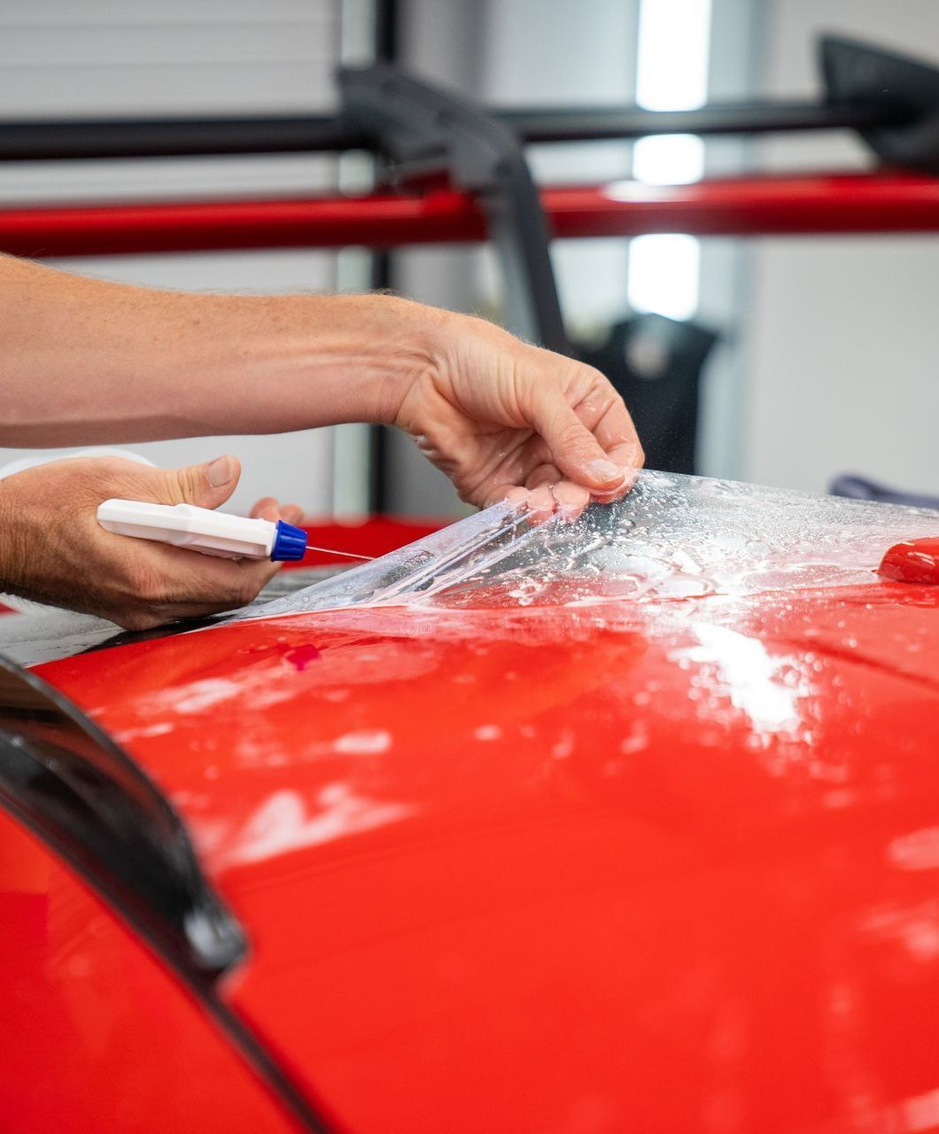 A person is wrapping a car with clear plastic