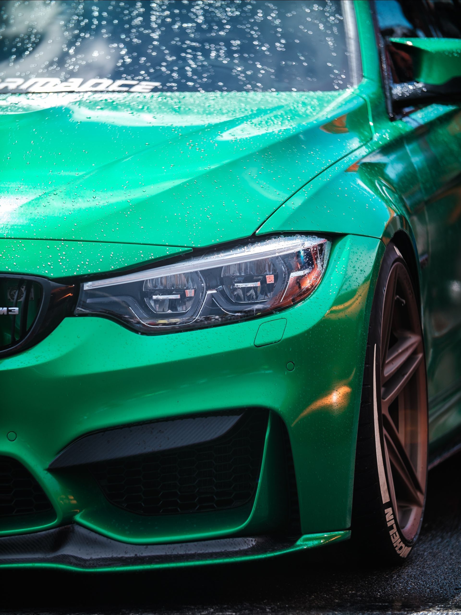 A green car with black wheels is parked in a garage.