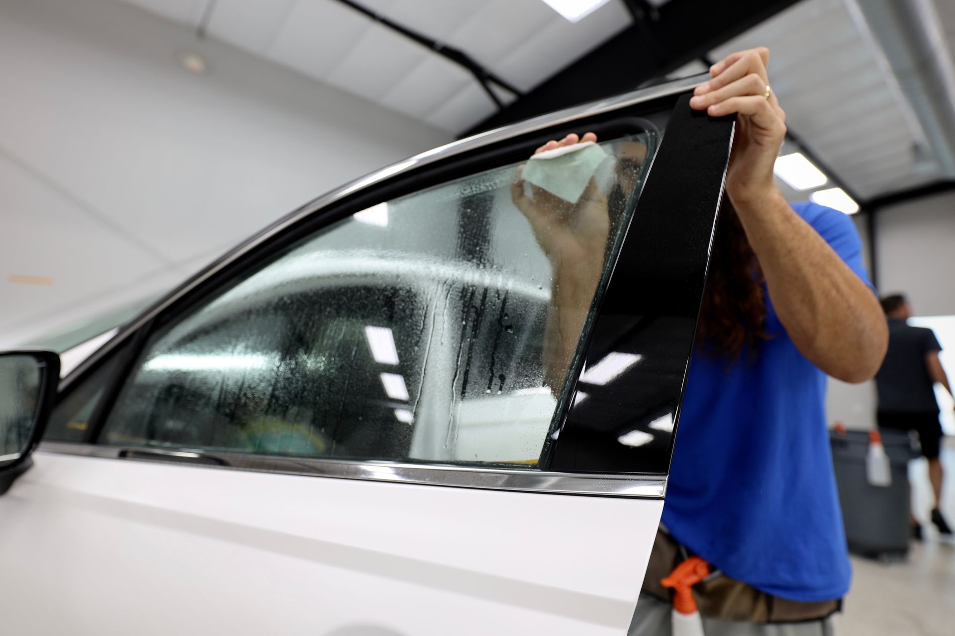 A person is applying tinted glass to a car windshield.