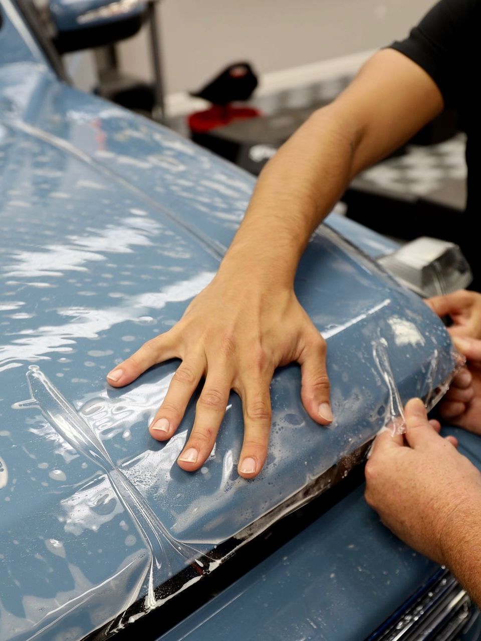 A silver car is being washed with soap and water