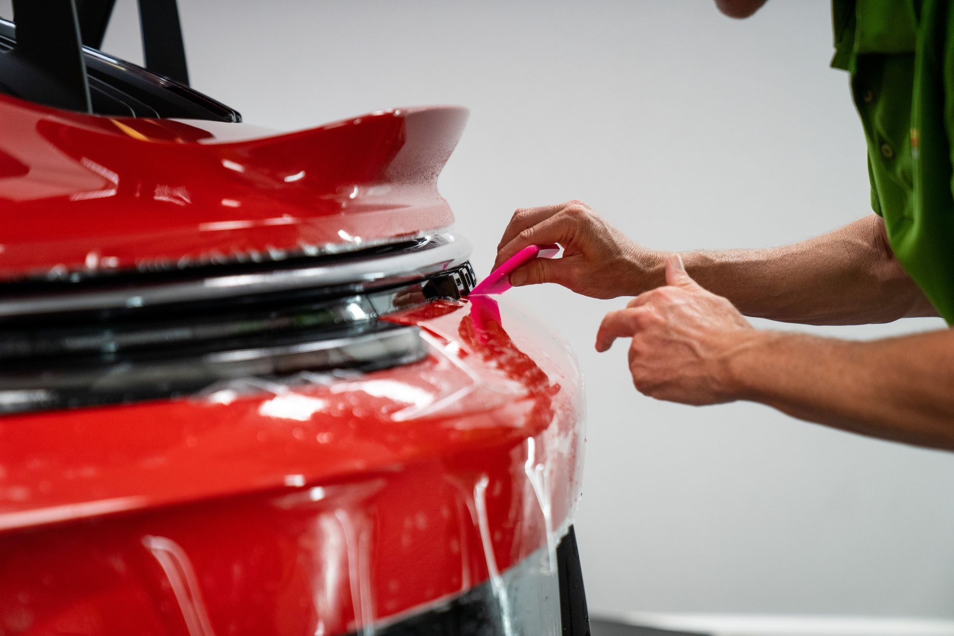 A person is cleaning a car with a blue sponge.