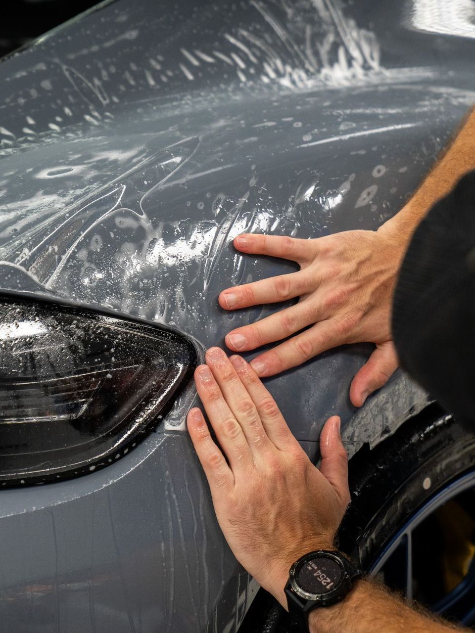 A person is washing a car wheel with foam