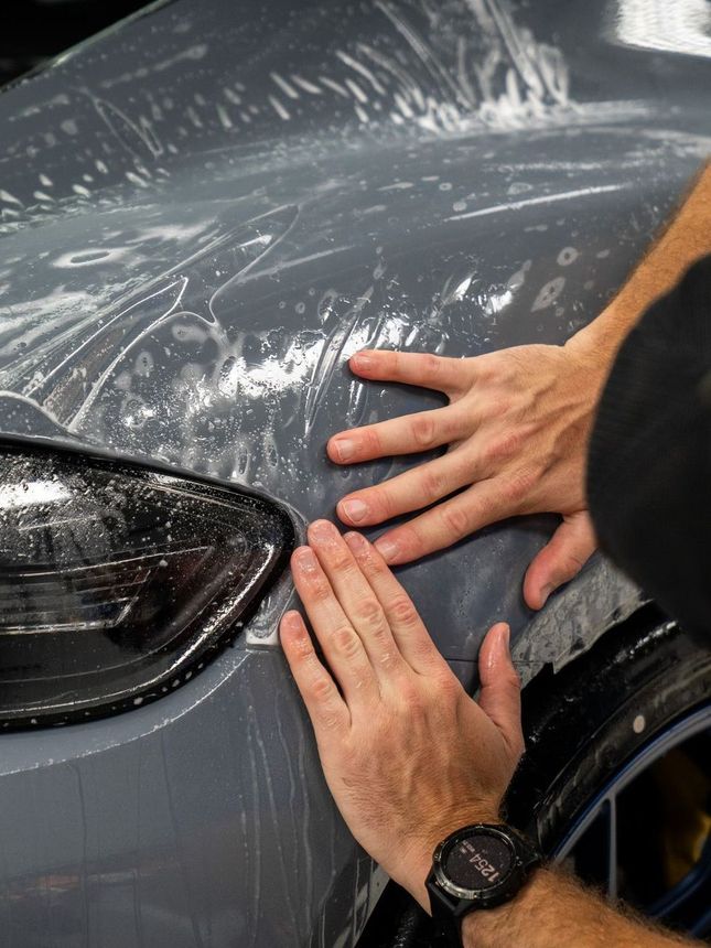 A person is washing a car wheel with foam